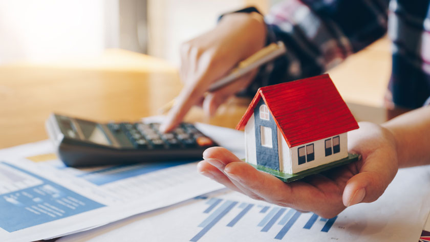 Woman holding house model in hand and calculating financial char